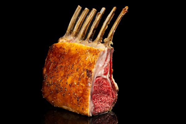 Close-up of the rack of lamb against a dramatic black background. 