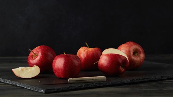 Red apples being sliced on a slate chopping board
