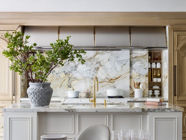 The “entertainer’s kitchen” in the McCroskey Interiors-designed Brookside home features a Gaggenau induction cooktop and ovens, while gold fixtures enhance the gold veining in the sliding marble backsplash. Photography by Nate Sheets.