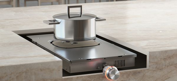 A kitchen island cutaway that reveals the unseen induction cooktop mechanism underneath
