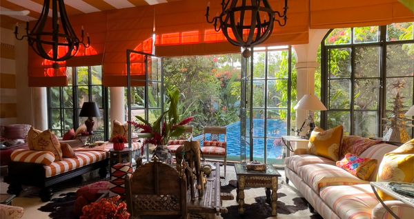 A gorgeous Mexican living room with doors leading out to a sparkling pool, featured in Newell Turner's book, Mexican: A Journey through Design. 