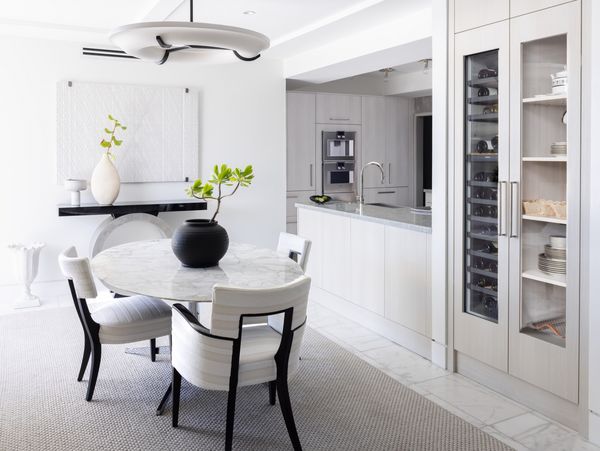 The cleanly designed dining room in Jonathan Savage's stylish Ibis Isle condominium in Palm Beach, with a Gaggenau wine cabinet to the side and the kitchen full of Gaggenau appliances just beyond the dining room. Photography by Adahlia Cole and Colin Peck.