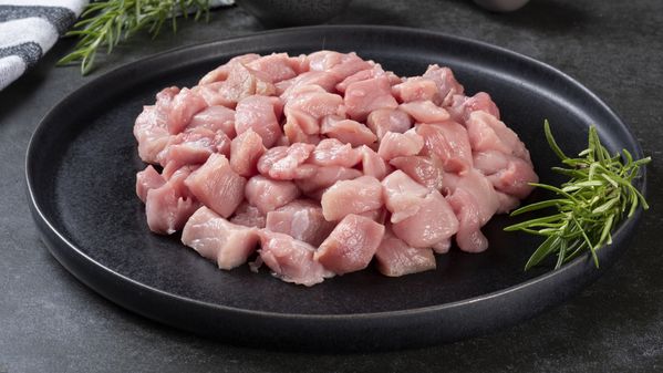 A dark plate containing diced chicken