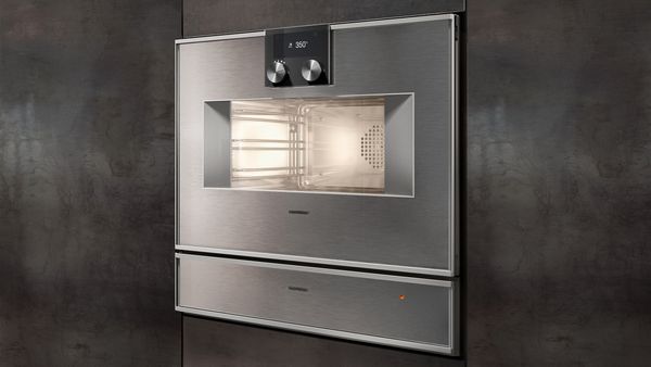 A Gaggenau combi steam oven and warming drawer installed in modern steel rolled furniture.