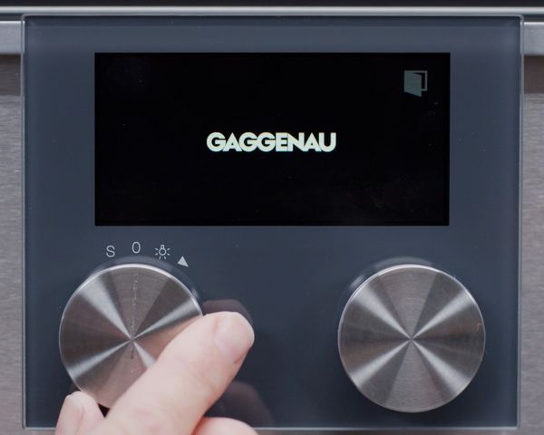 A hand adjusting the control knob on the Gaggenau Espresso System