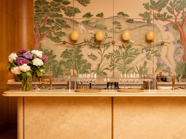 Quince's iconic bar, set against warm wood tones and wallpaper featuring a gorgeous forest scene. 