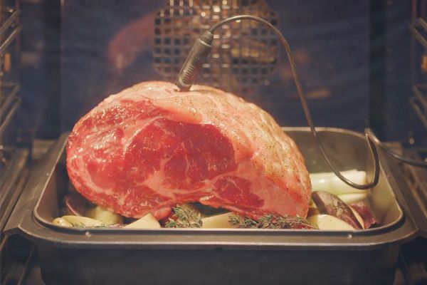 Gaggenau temperature probe inserted into a large piece of meat on a bed of vegetables.