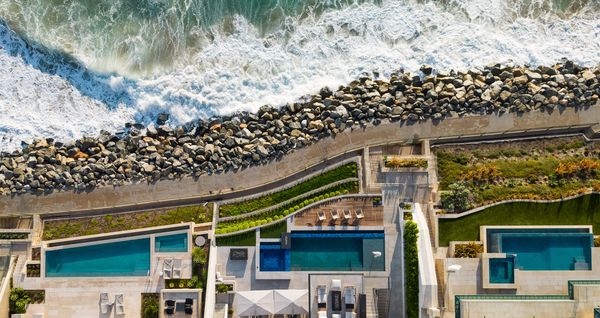 An aerial view of the Dana Point property, with it's glittering pool juxtaposed against the ocean waves rolling in nearby.