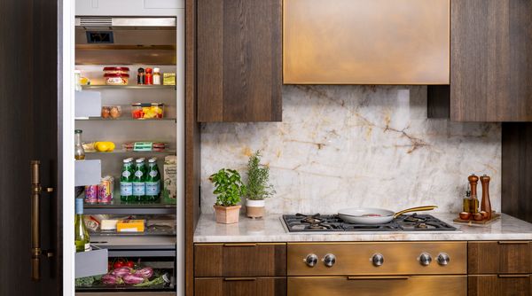 A detail shot of Jan Mengenhauser's home kitchen, featuring her Gaggenau fridge behind custom cabinetry and the Gaggenau cooktop that inspired the brass elements in her home. 