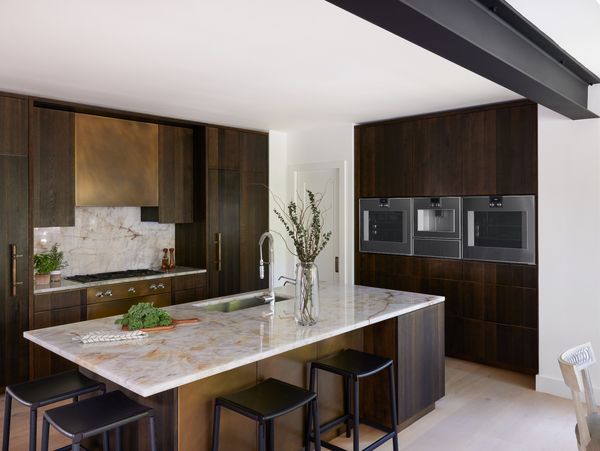 Jan Mengenhauser's home kitchen, with warm wood tones and brass complimenting her Gaggenau appliances. 