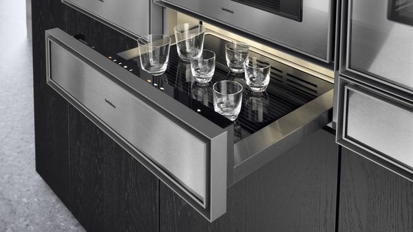 An open Gaggenau culinary warming drawer warming various coffee glasses 