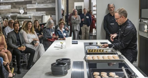 Chef Johnny Spero prepares canapés on a Gaggenau cooktop in front of guests.