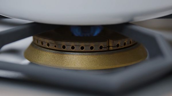 Close-up of the flame from one of the high output burners of a Gaggenau 5 Burner Vario Gas Cooktop heating a saucepan 