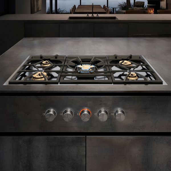 A Gaggenau 5 Burner Vario Gas Cooktop installed in a luxury kitchen with the center burner gas flame visible