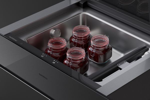 Close-up of the Gaggenau Minimalist series vacuuming drawer shown open with jars of fruit preserves