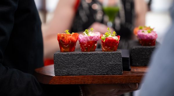 Colorful floral bites are served to guests on a black stone platter.