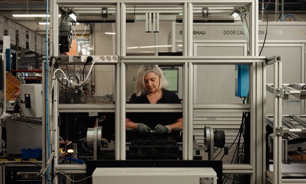 A worker at the Gaggenau factory in Lipsheim assembles an expressive oven control ring, surrounded by equipment