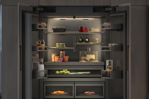 Blick ins Innere einer Kühl- und Gefrierkombination der Gaggenau Vario Kältegeräte Serie Expressive, der die blendfreie Beleuchtung und die Innenoberflächen aus dunklem, gebürstetem Edelstahl zeigt