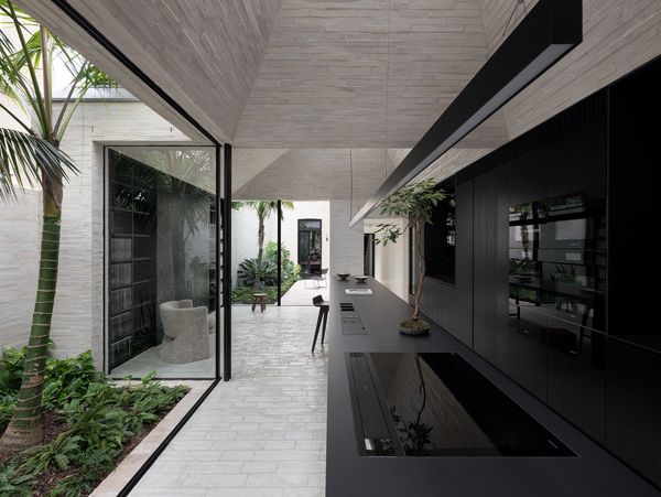 Sleek, all-black kitchen featuring a Gaggenau 400 series induction cooktop with integrated ventilation on the island.