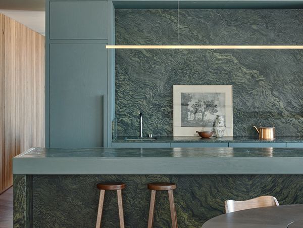 A kitchen with blue-green cabinets and a Gaggenau full surface induction cooktop set in green marble.