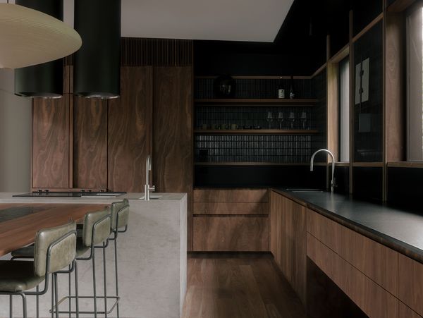 Sophisticated kitchen with a concrete island featuring Gaggenau Vario 400 series cooktops and dark wood cabinets.