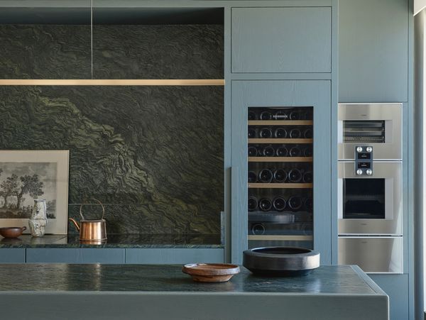 Blue-green kitchen with a Gaggenau wine climate cabinet and 200 series ovens built into the cabinetry.