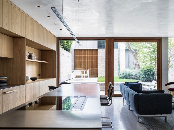 Modern kitchen with a Gaggenau 400 series downdraft ventilation on a large island opening to a garden.