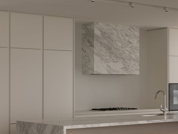 A minimalist kitchen with a marble island and extractor hood, featuring a Gaggenau Vario gas cooktop.