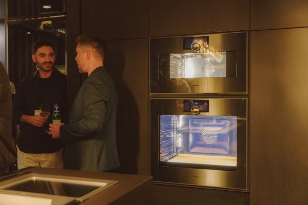 Individuals engaged in conversation with Gaggenau appliances in the background.