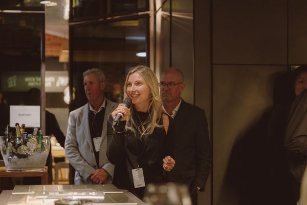 A woman with a microphone speaks to guests at an event.