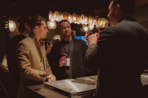 Guests engaged in conversation, with Gaggenau appliances in a stylish kitchen interior.