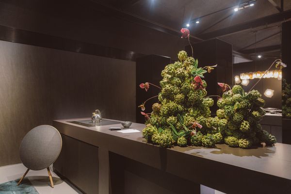 A modern kitchen featuring Gaggenau appliances with striking floral arrangements as the focal point.