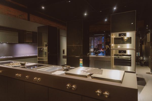 A sleek kitchen space showcasing Gaggenau ovens and cooktops with a minimalist grey and black design.