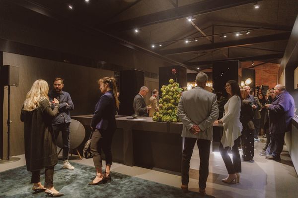 A gathering in a beautifully designed kitchen displaying Gaggenau appliances, with attendees socializing and enjoying the event.