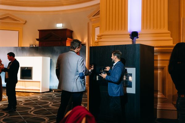 Two men discussing near Gaggenau appliances displayed on a counter.