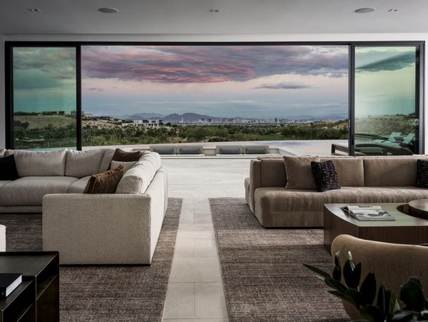 Wide-spanning windows off the living room space showcase the dazzling Las Vegas skyline at sunset. 