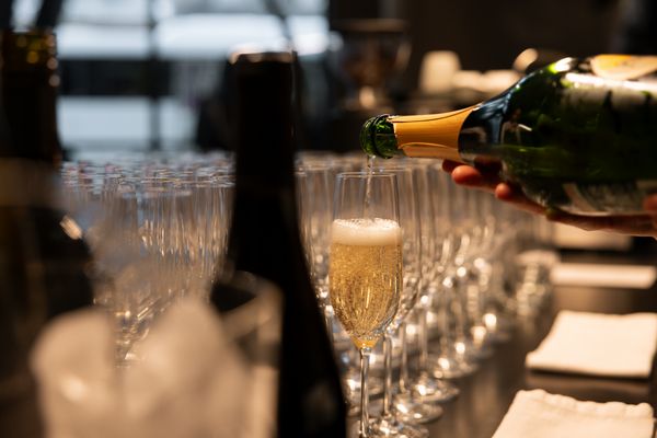 A hand pours sparkling champagne from a bottle into a glass.
