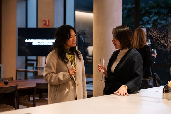 Two women enjoy a conversation with wine at a modern kitchen counter. 