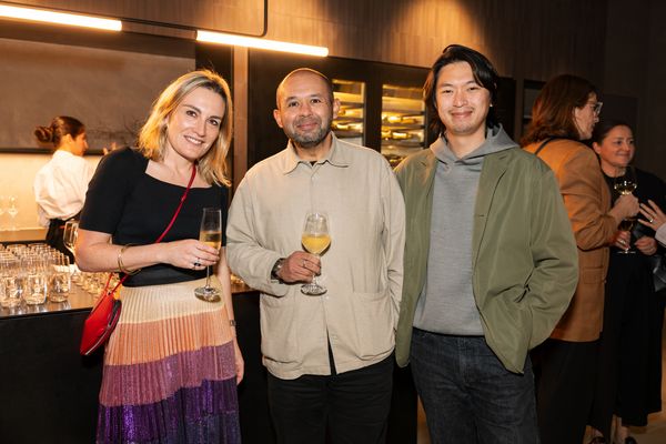 Three people at the Gaggenau KOTY Awards, standing next to a Gaggenau wine climate cabinet.