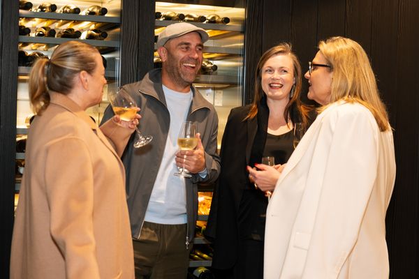 Four people laughing at the Gaggenau KOTY Awards next to a Gaggenau wine cabinet.