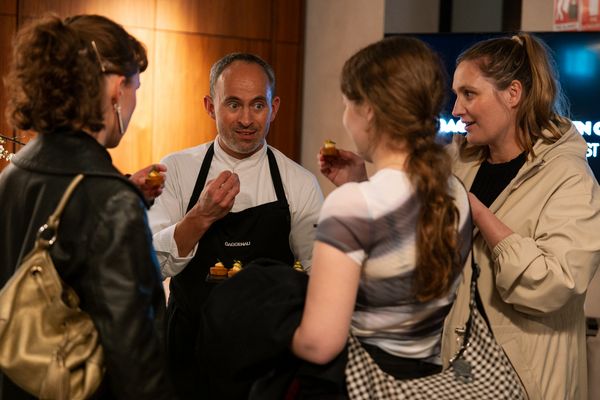 A chef in a Gaggenau apron enthusiastically talks with three guests.