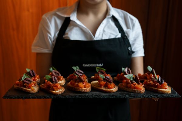 A server in a Gaggenau apron presents a slate of bruschetta.