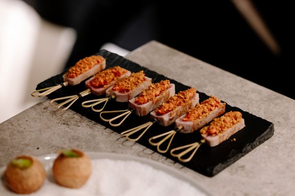 Seared tuna canapés with a crumb topping on a slate platter.