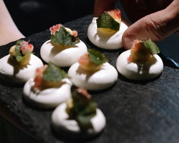Bauhaus-inspired meringue canapés with herbs and roe on a slate.