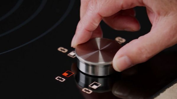 Close-up view of an owner using the twist knob of a CI induction cooktop