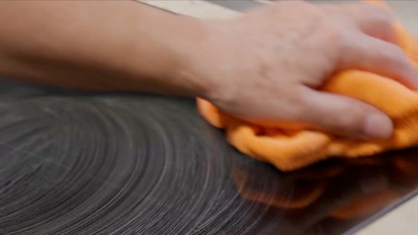 Close-up view of an owner cleaning the CI induction cooktop glass with hot soapy water