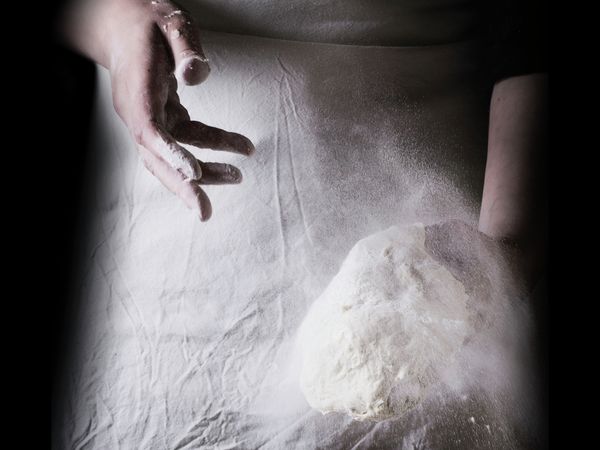 Baker throwing flour onto fresh dough