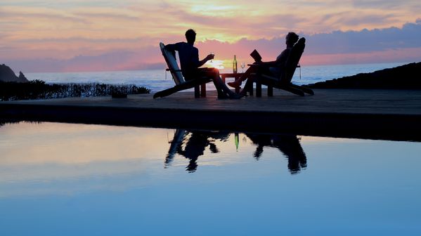 Couple relaxing by a pool while watching the sun set 